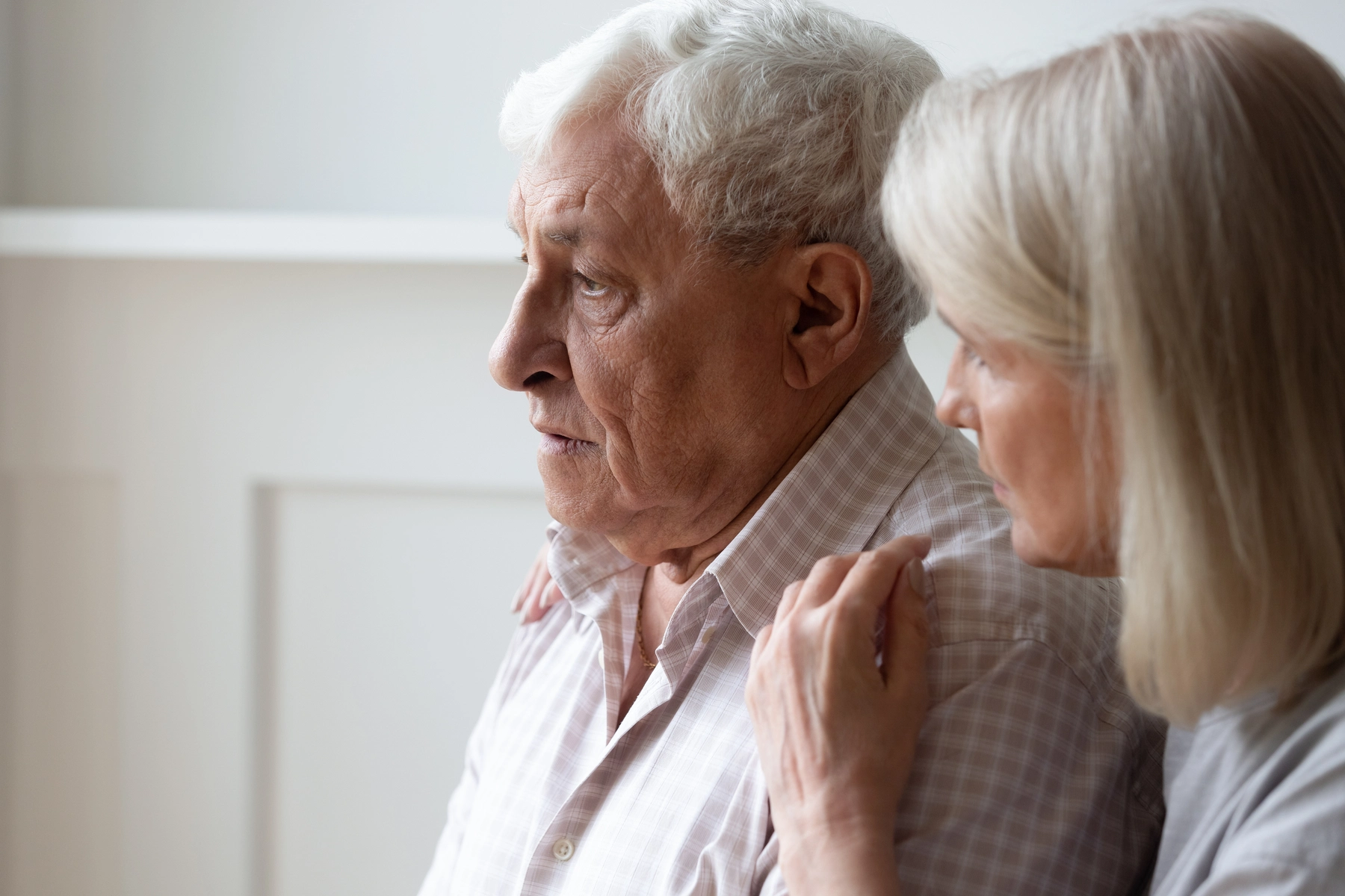 Image of an elderly man with an elderly spouse caregiver, both looking concerned
